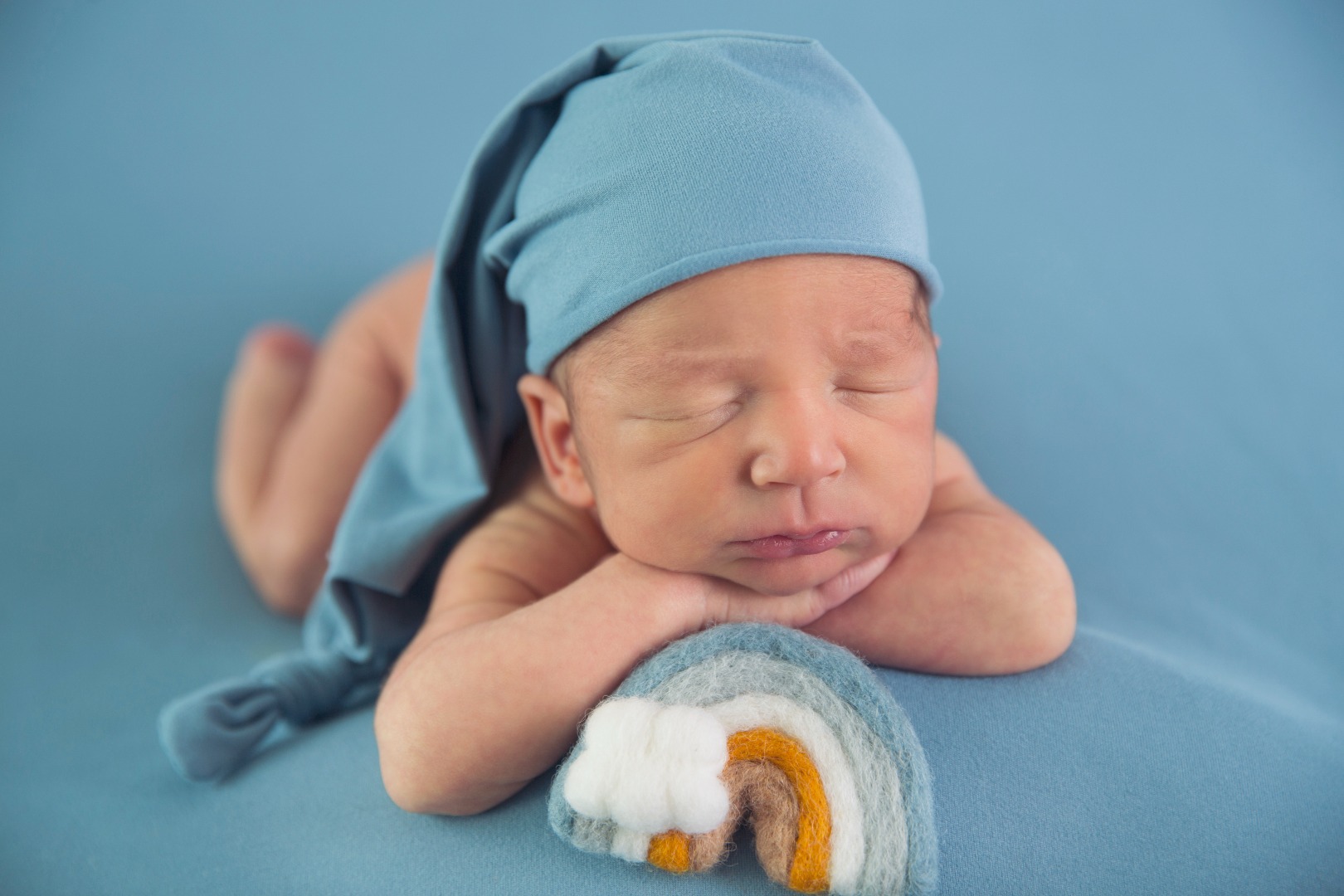 newborn baby in a sleep hat with a rainbow