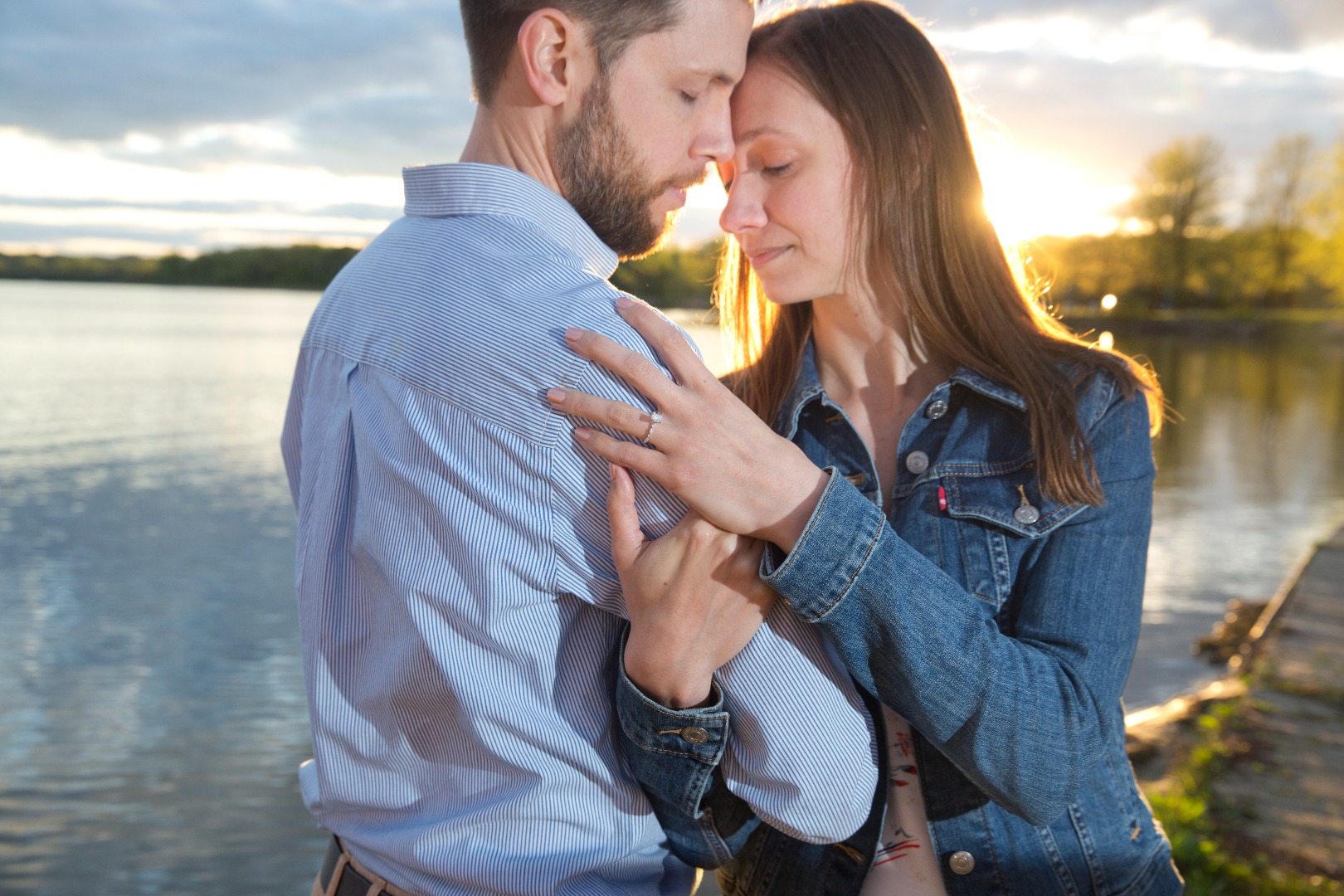 engaged couple snuggle at sunset