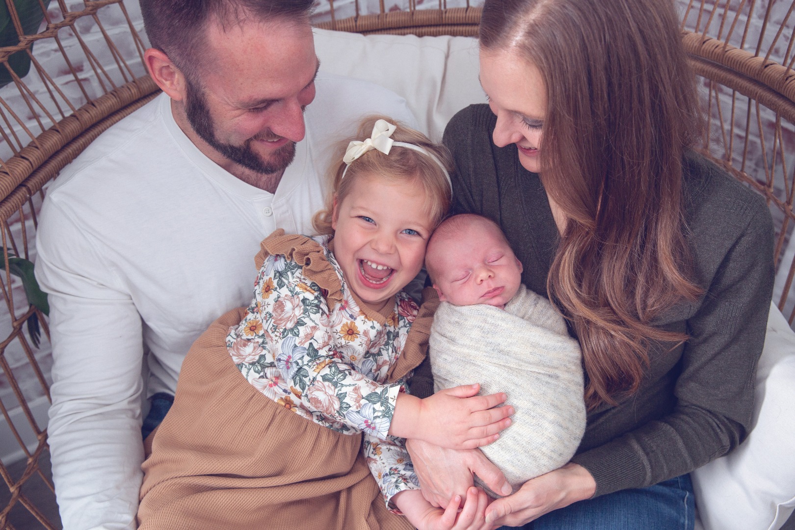 big sister laughs in joy with her new baby brother