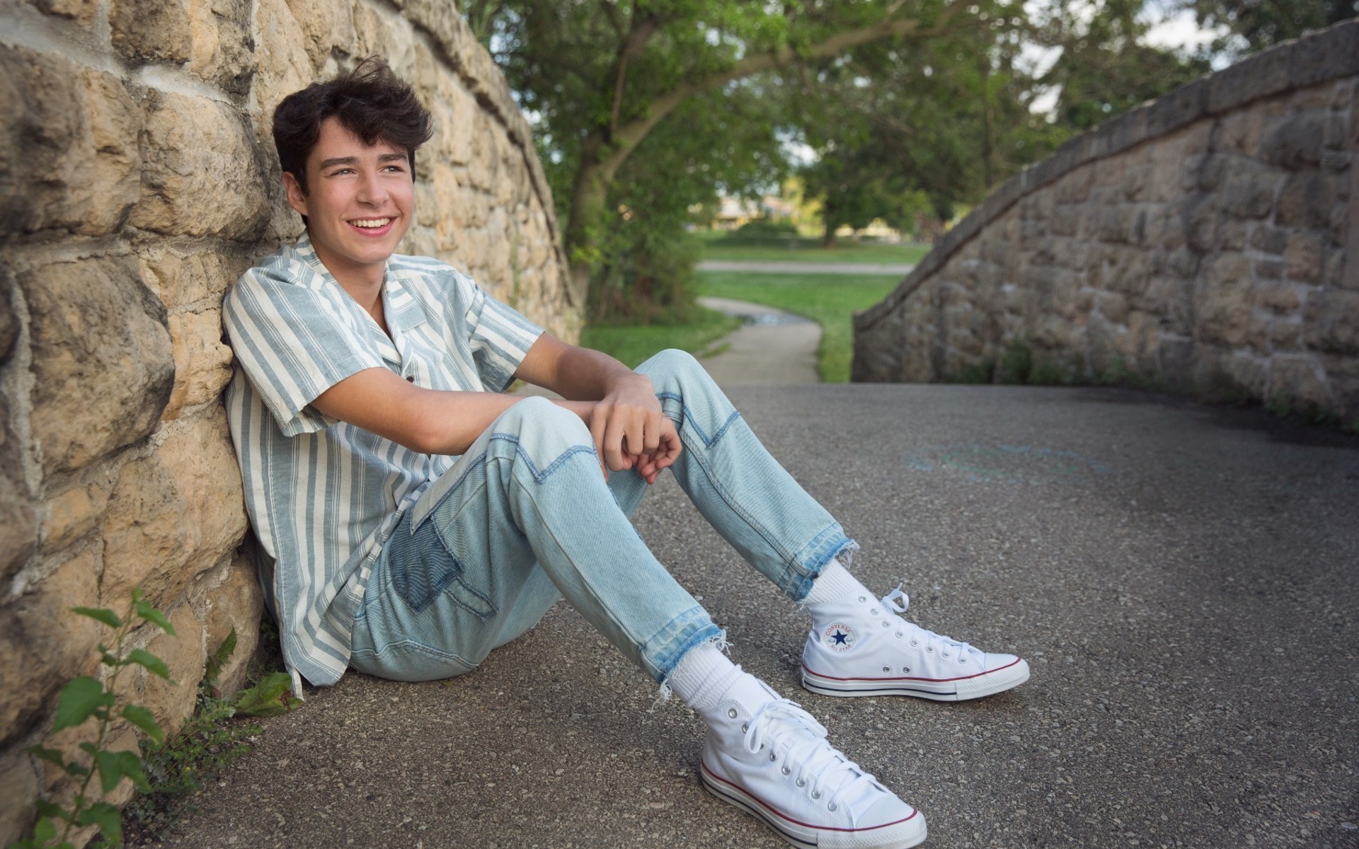 hs senior boy sits on a stone bridge