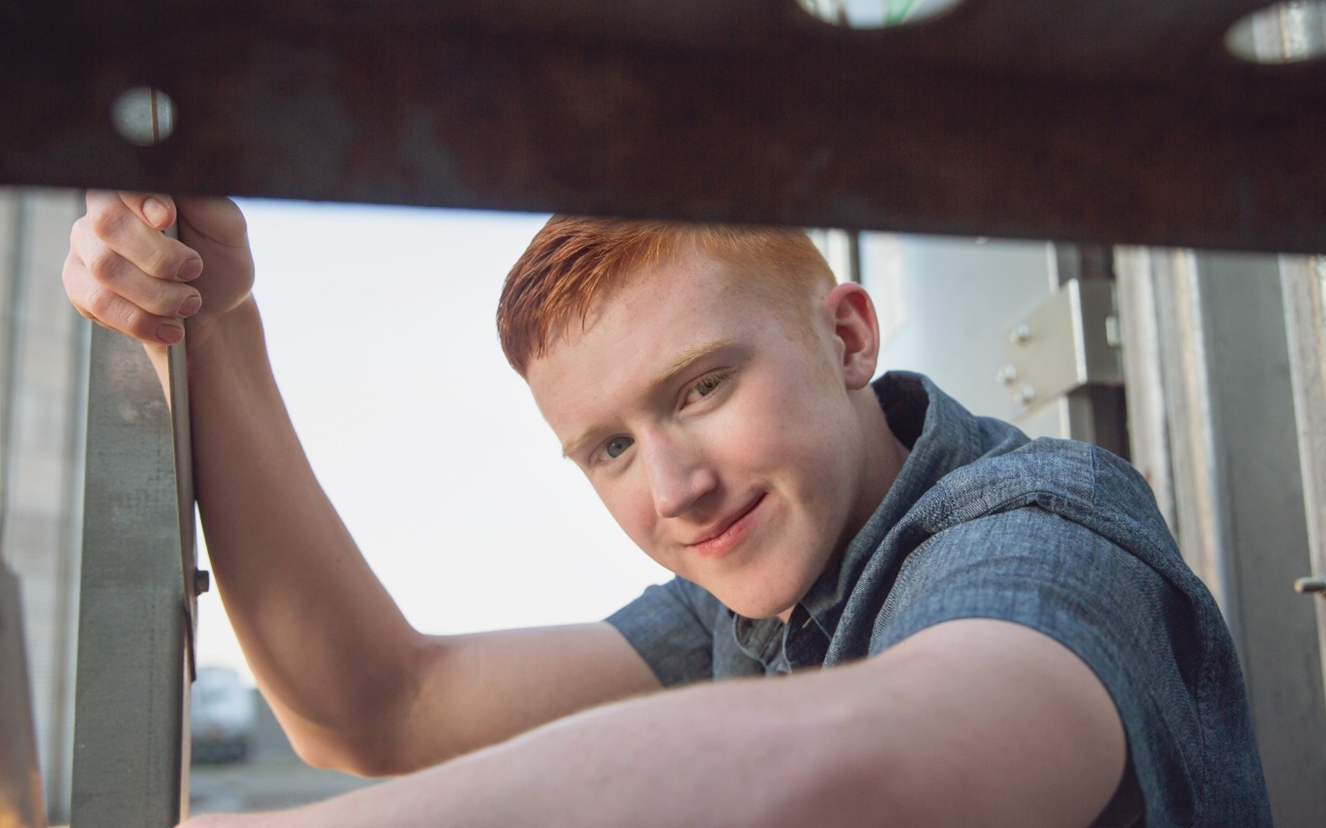 hs senior boy peeks throw the underside of a metal stair step