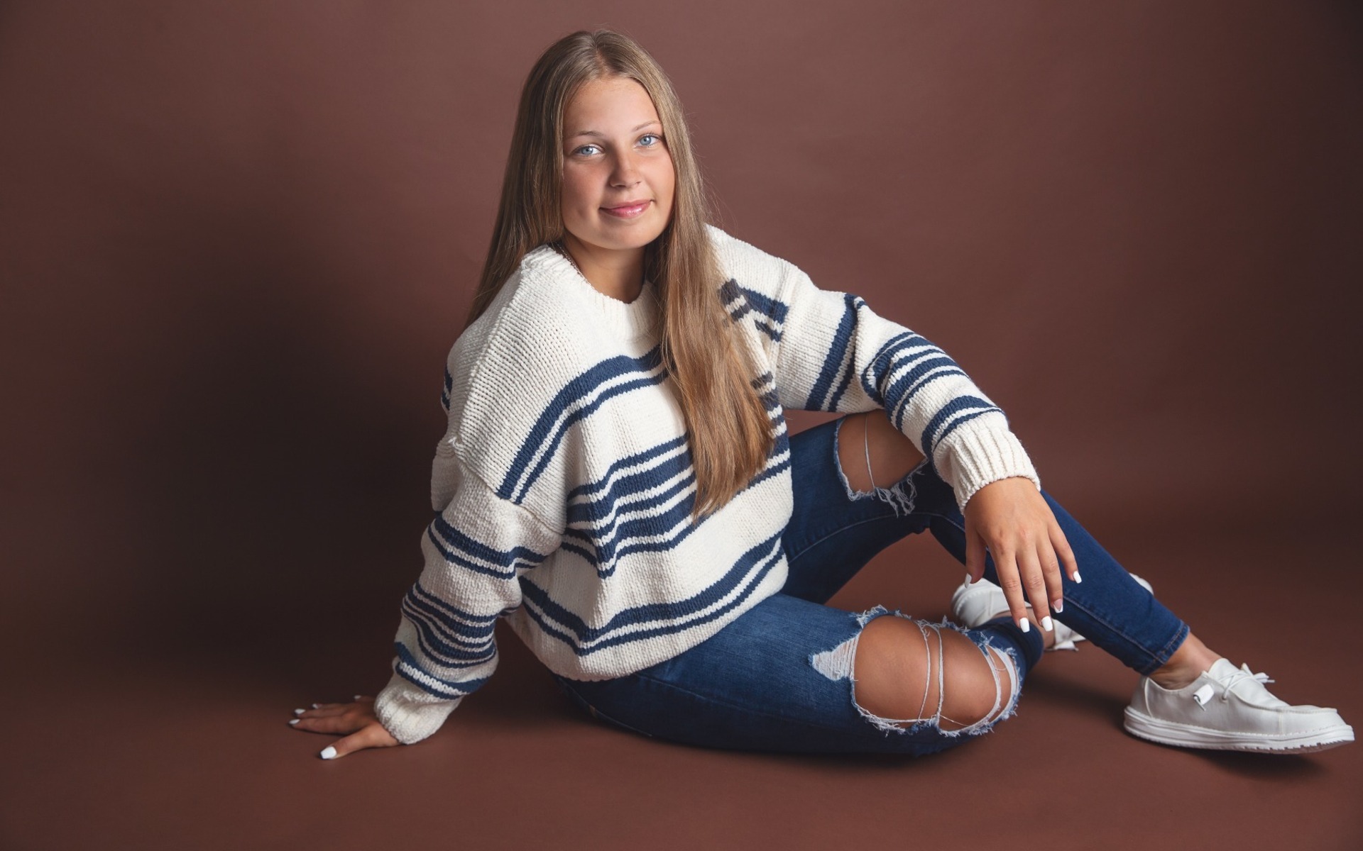 hs senior girl on a brown backdrop poses 