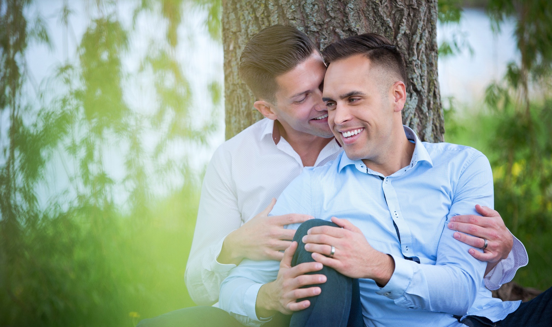 two men snuggle beneath a tree