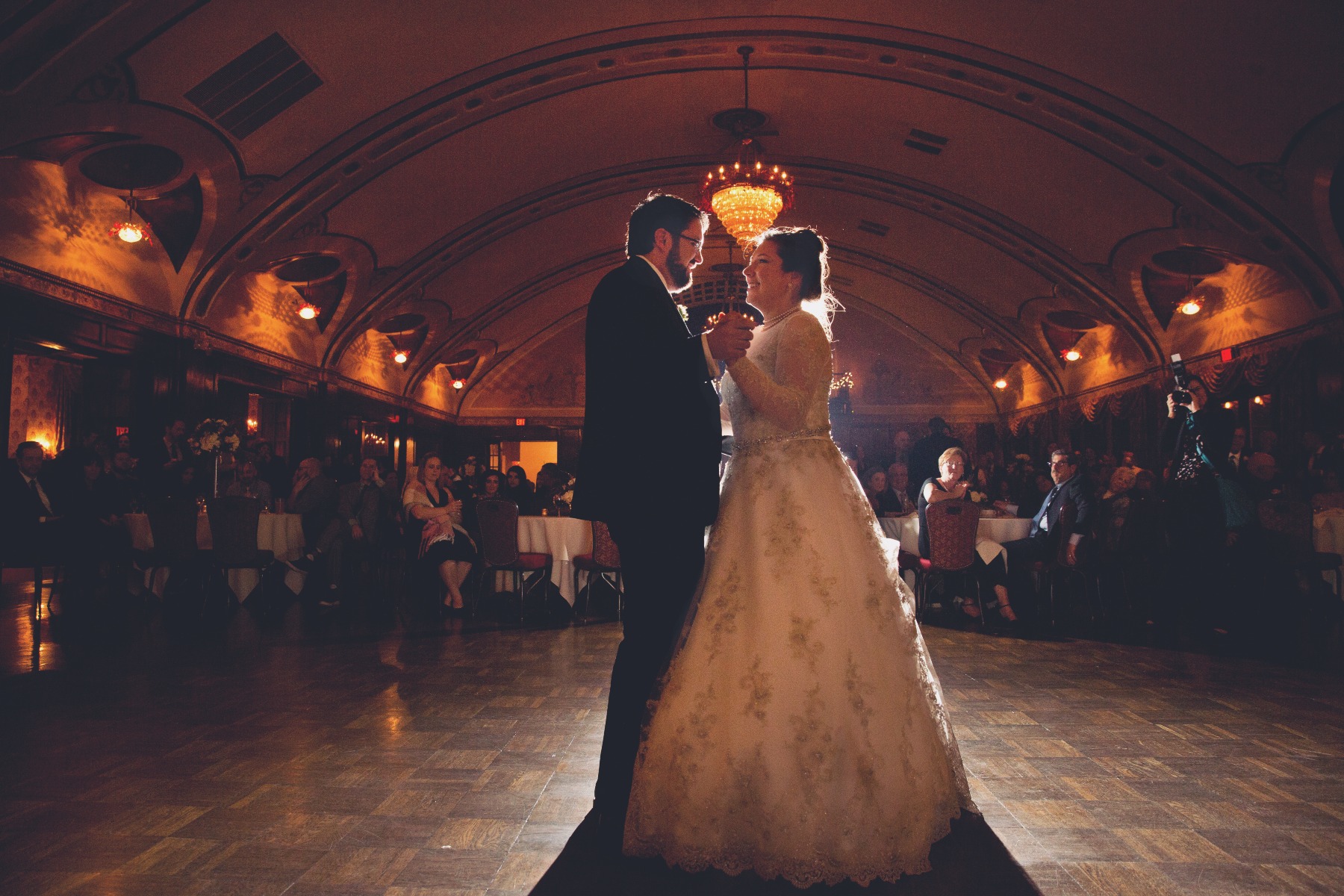 bride & groom dance in silhouette beneath a curved roof