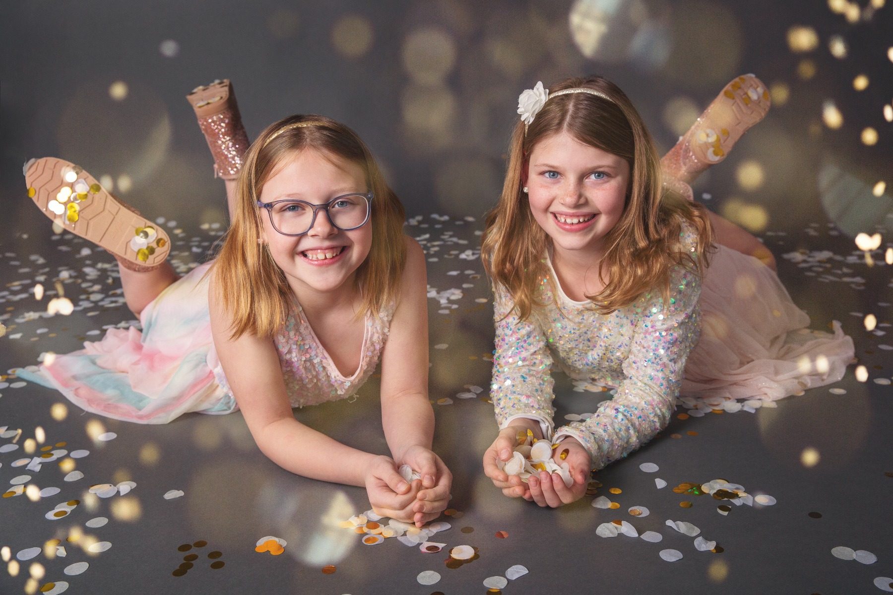 two girls lay on their bellies amongst a shower of glitter