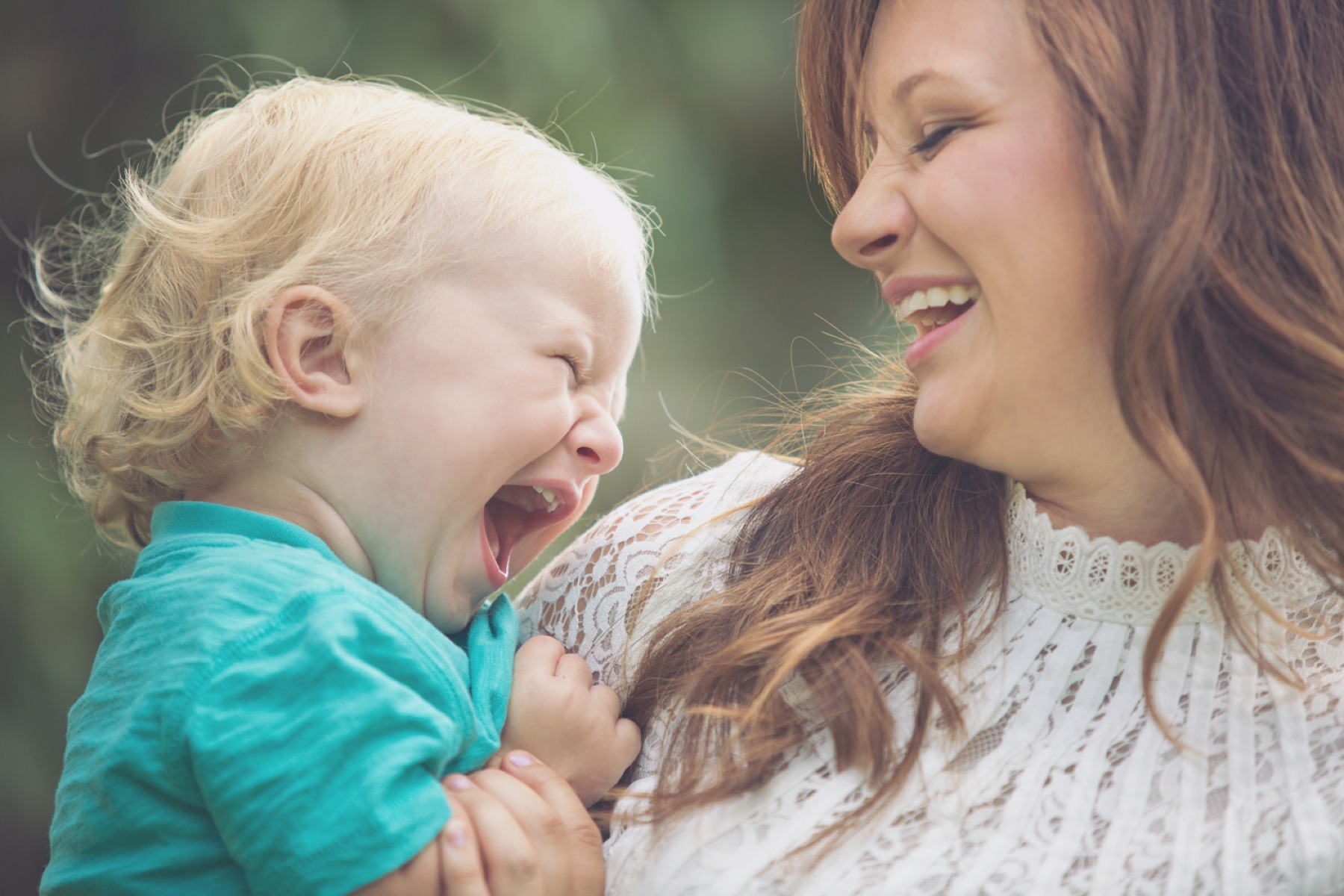 little boy laughs in moms arms