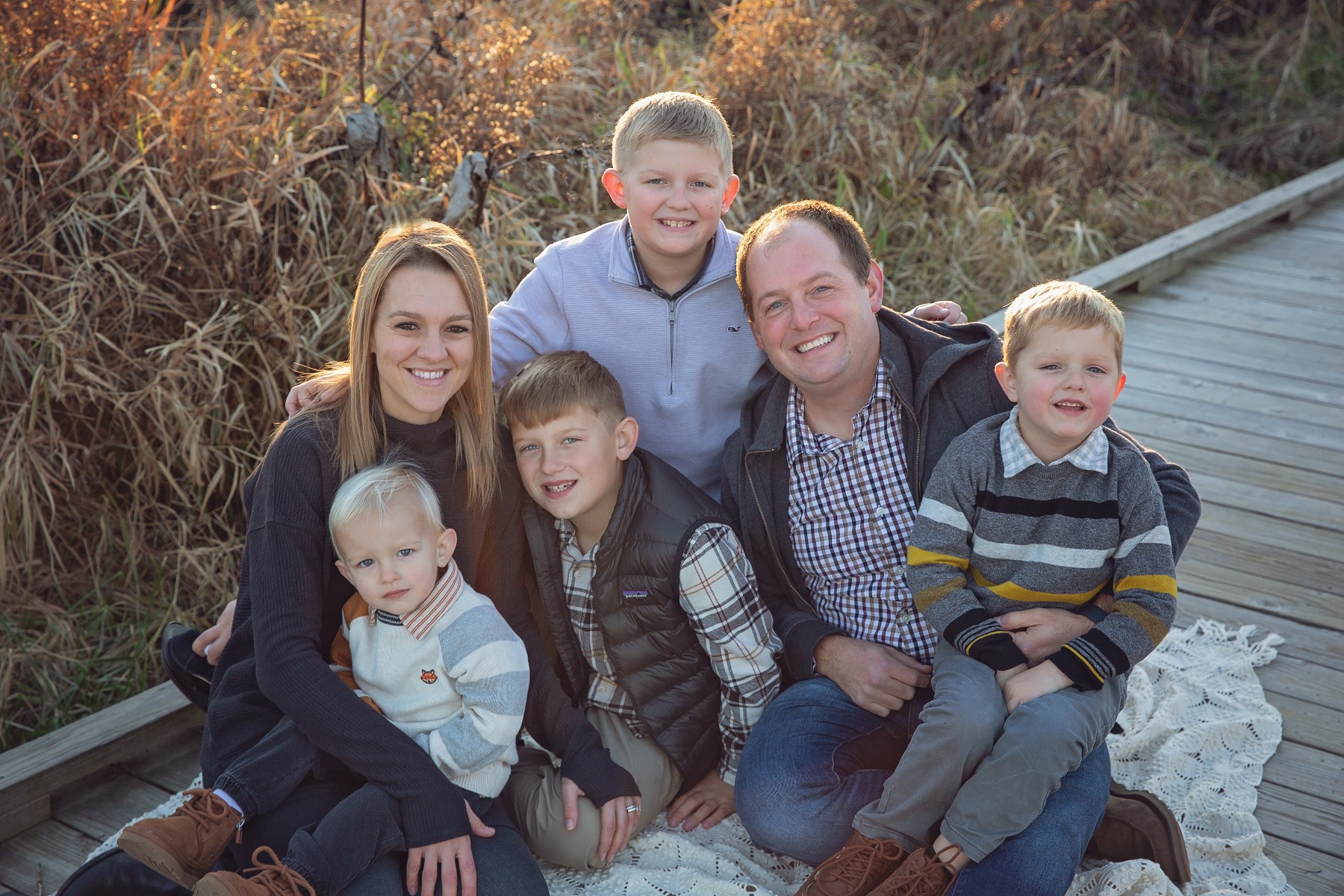 family of 6 snuggle on a wooded boardwalk