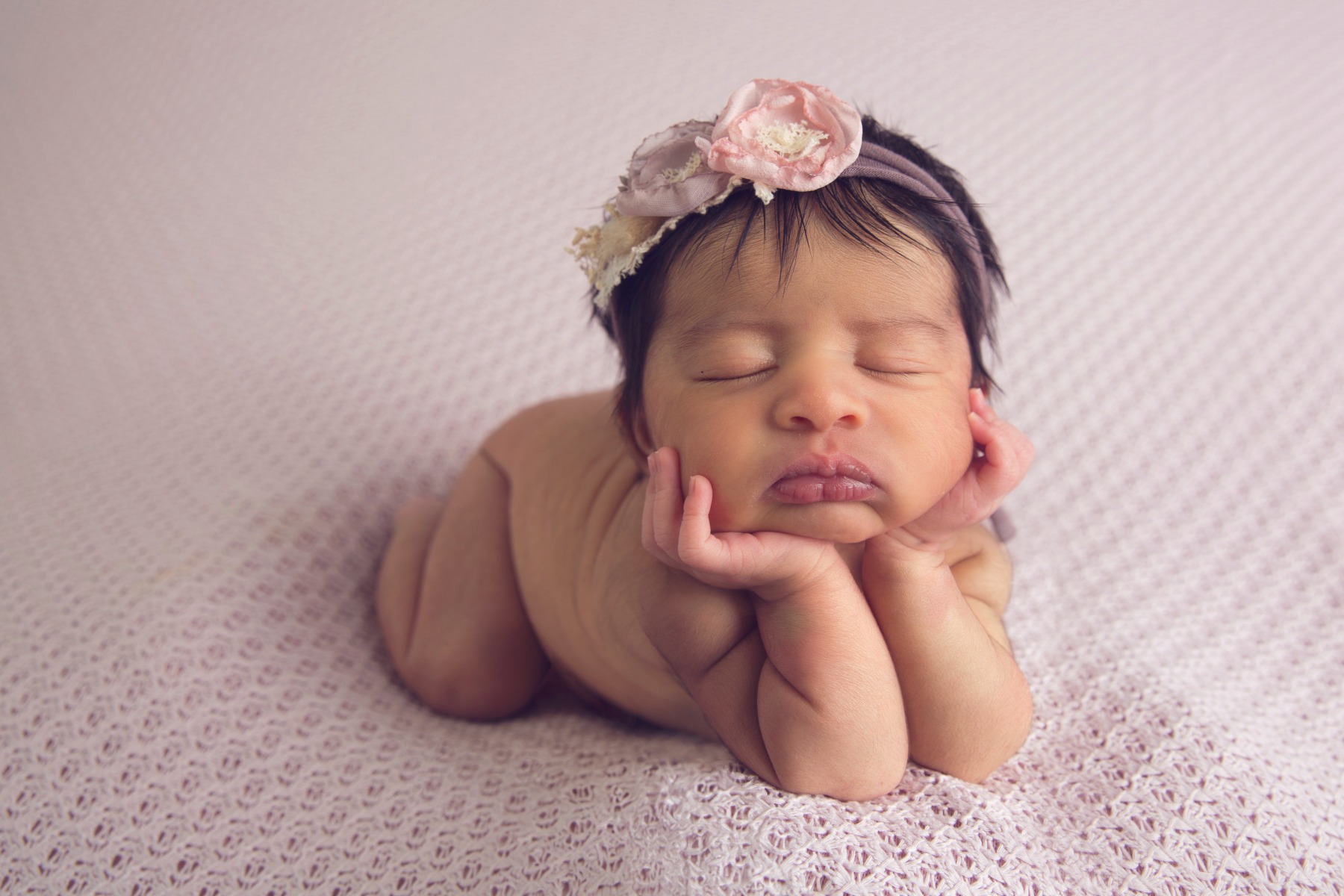 newborn baby sleeps with her chin in her hands