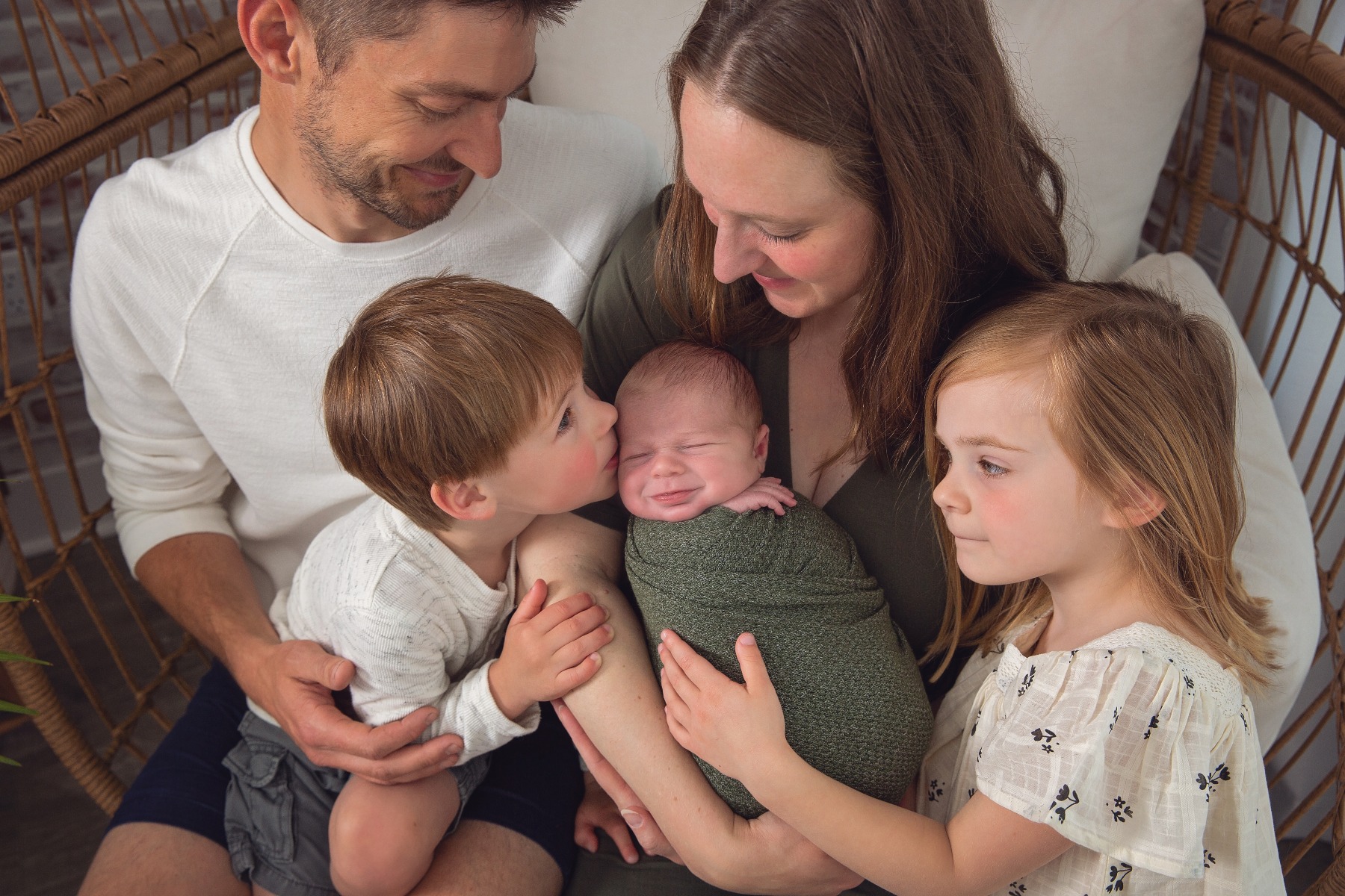 family snuggles their newborn baby