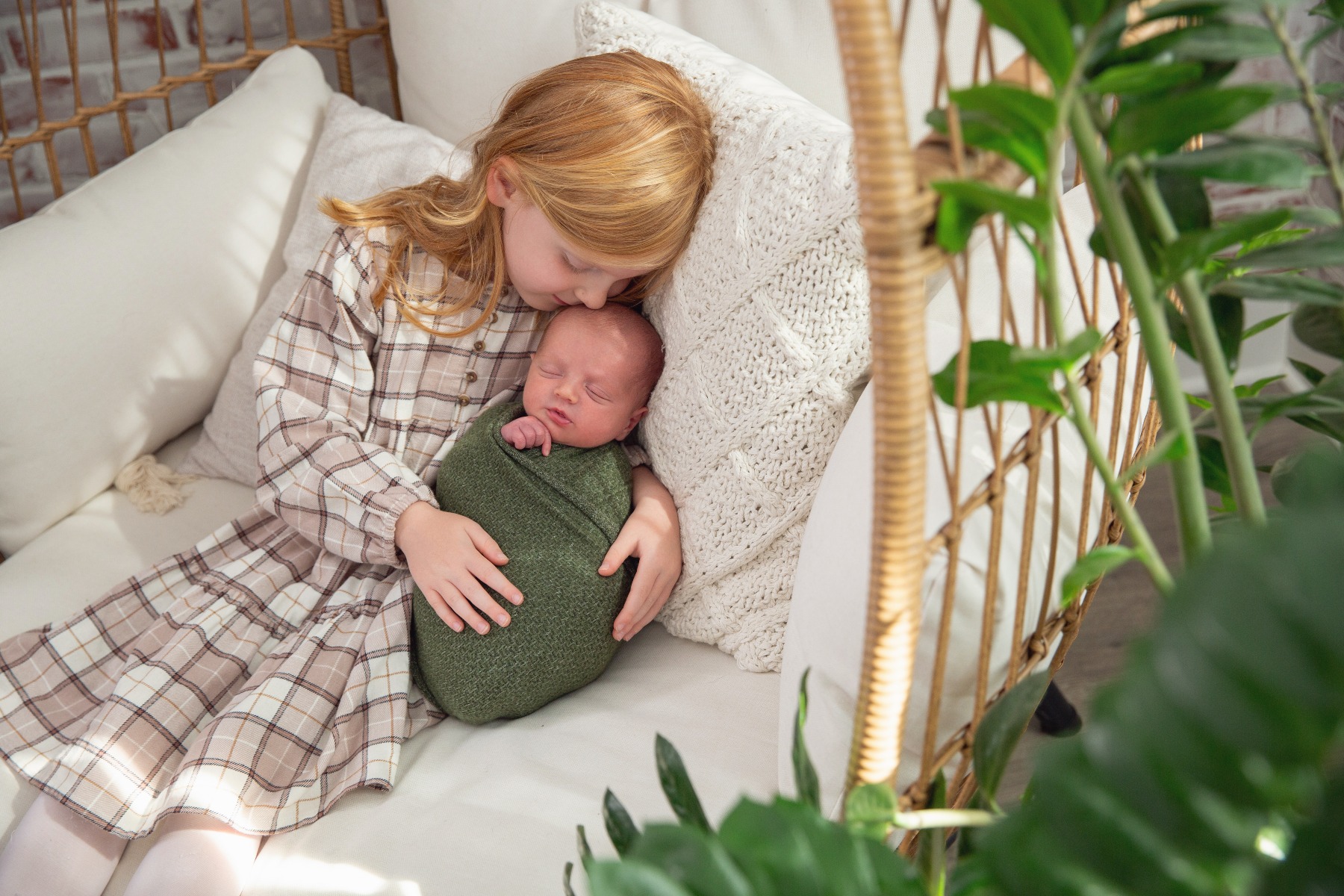 older sister snuggles her newborn brother