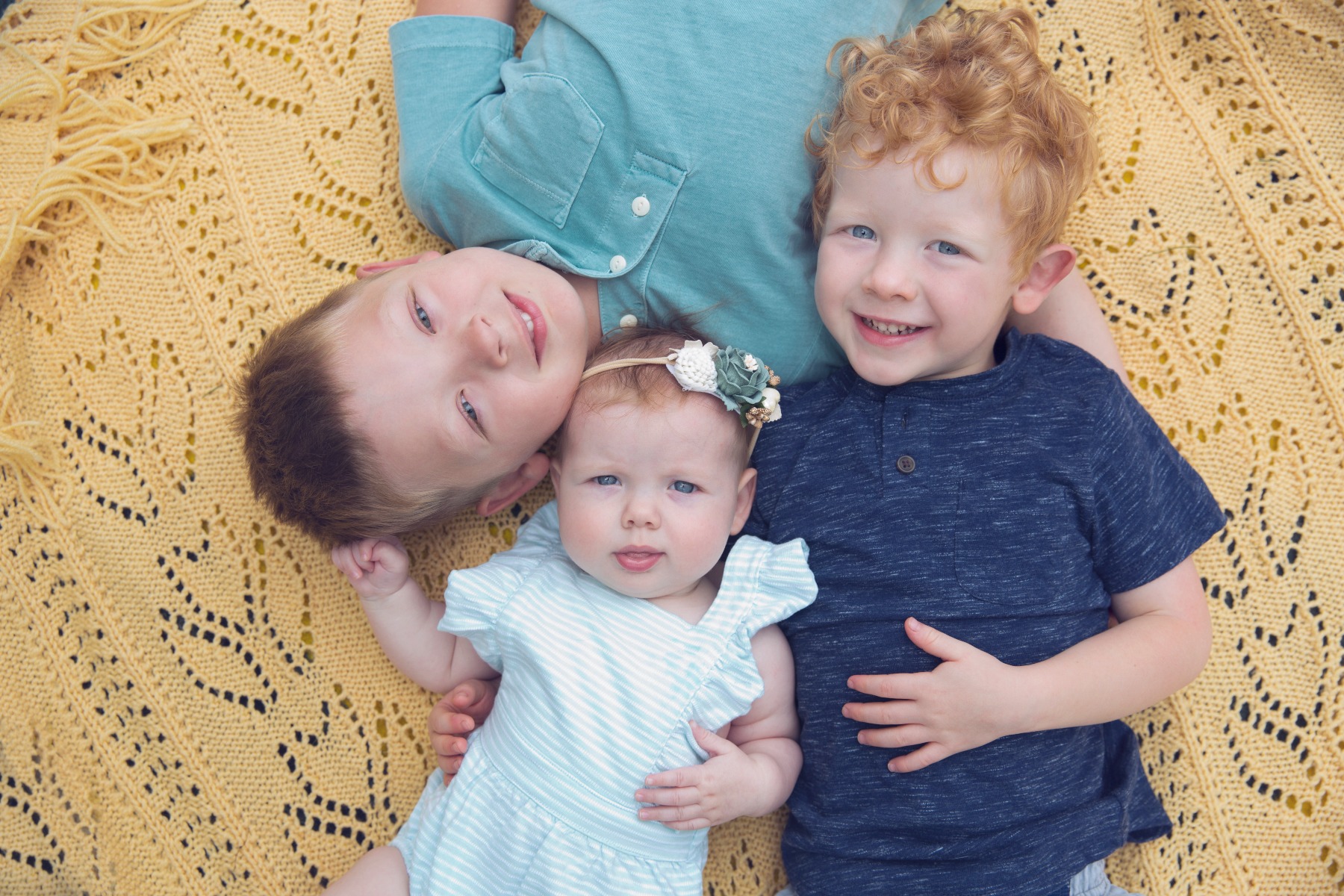 three siblings lay on their backs together