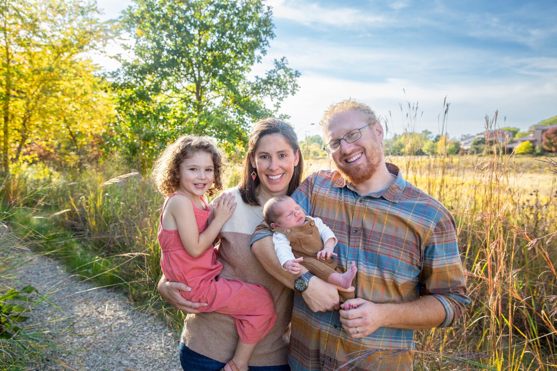 family of 4 stand on a sunny path