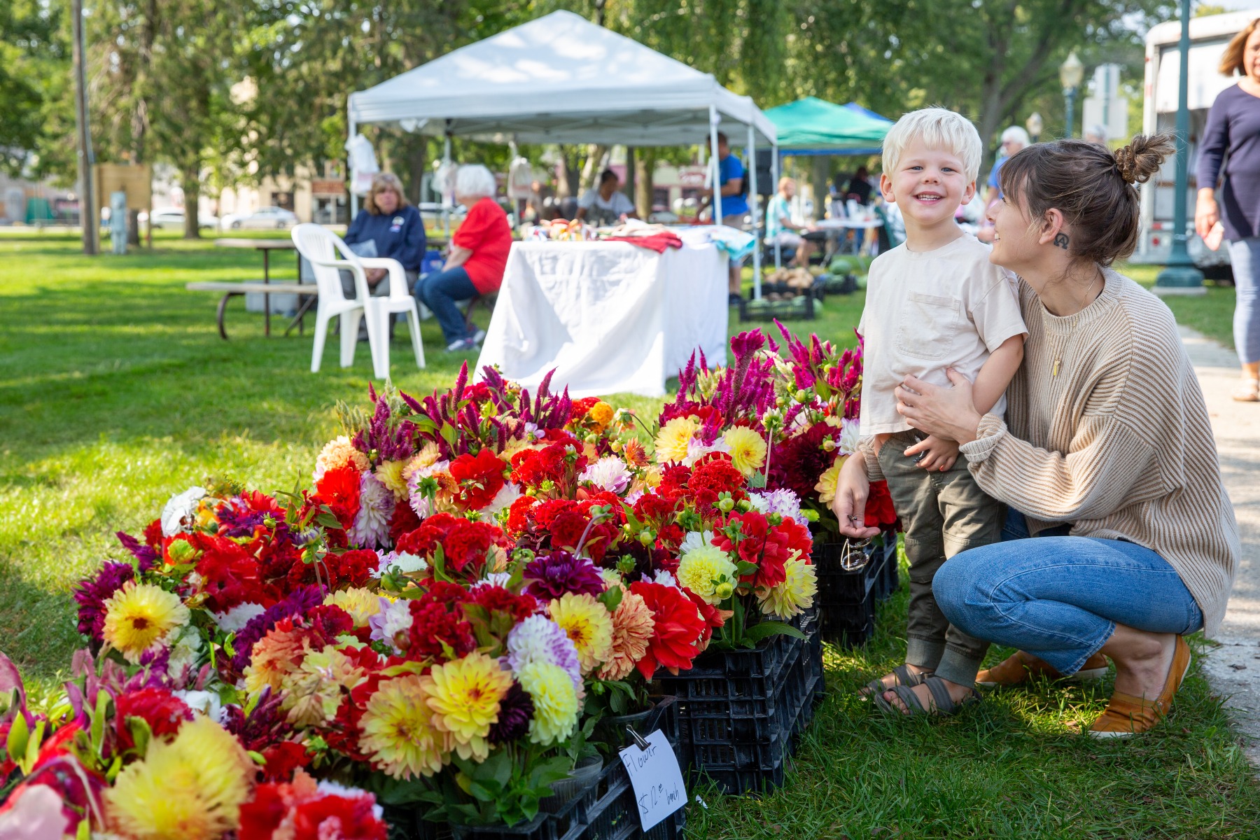little boy picks out flowers at a farmers market