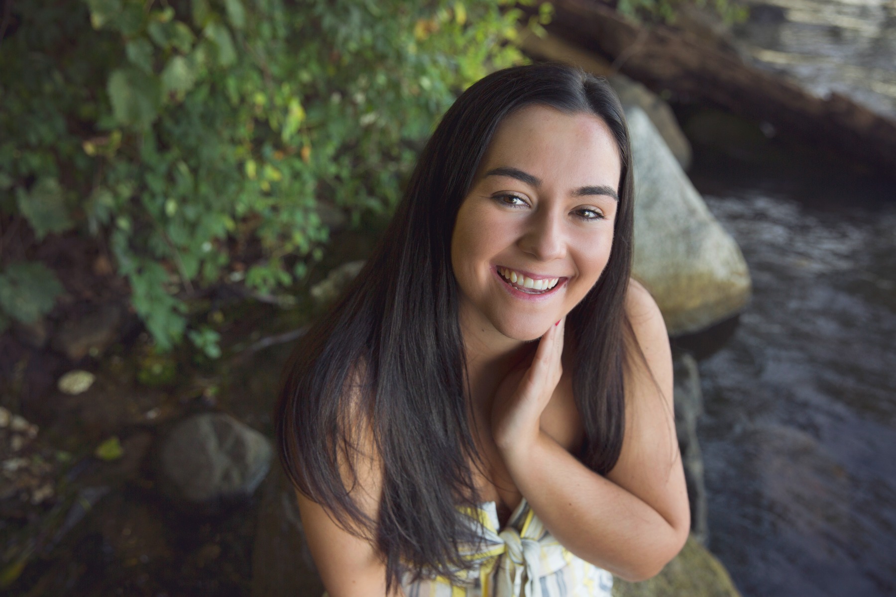 hs senior girl sits on the shore of a lake