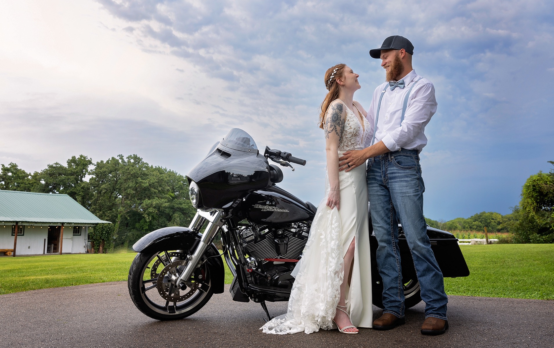 young newly married couple stands in front of their black motorcycle