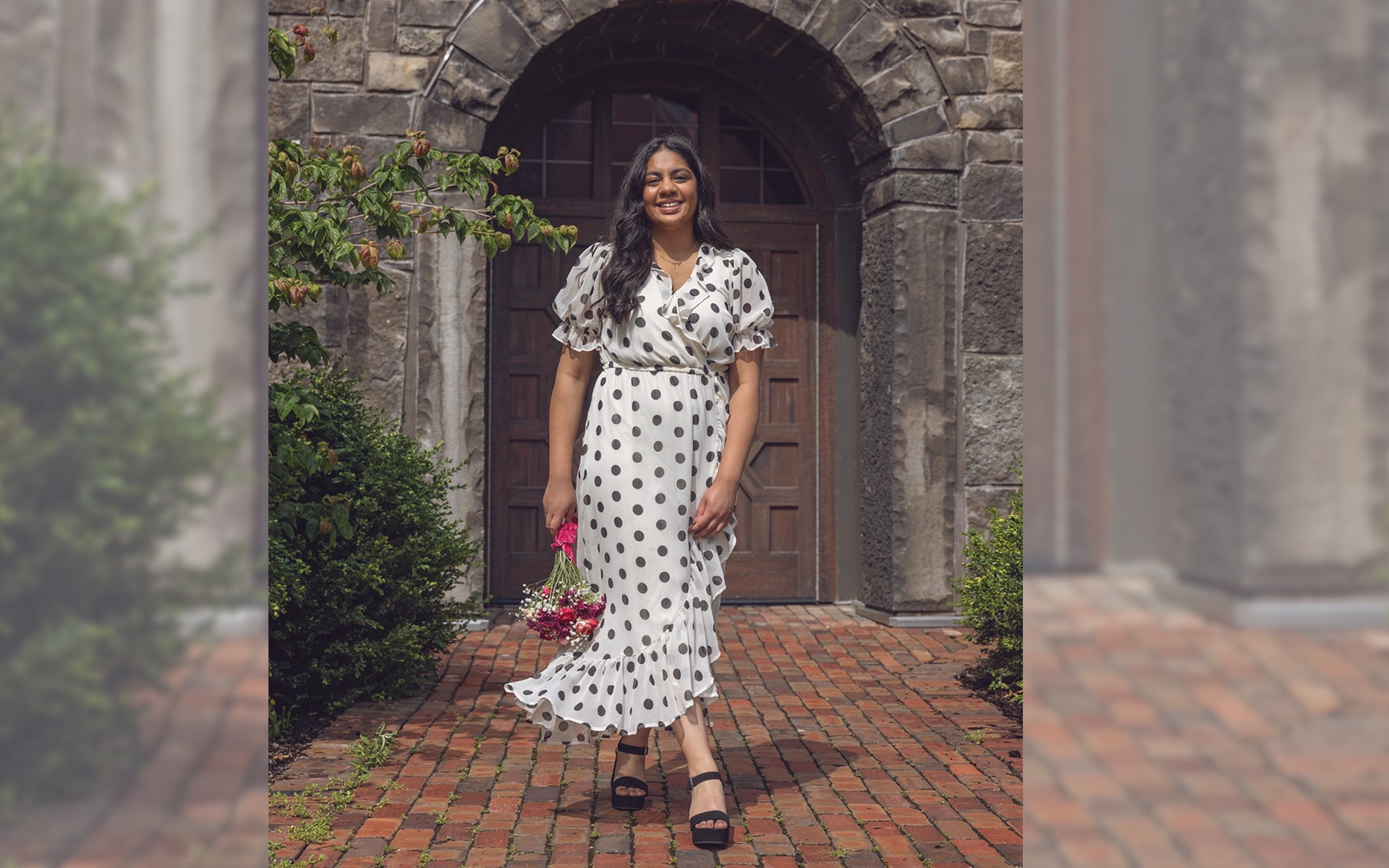 high school senior girls walks along a stone pathway all smiles
